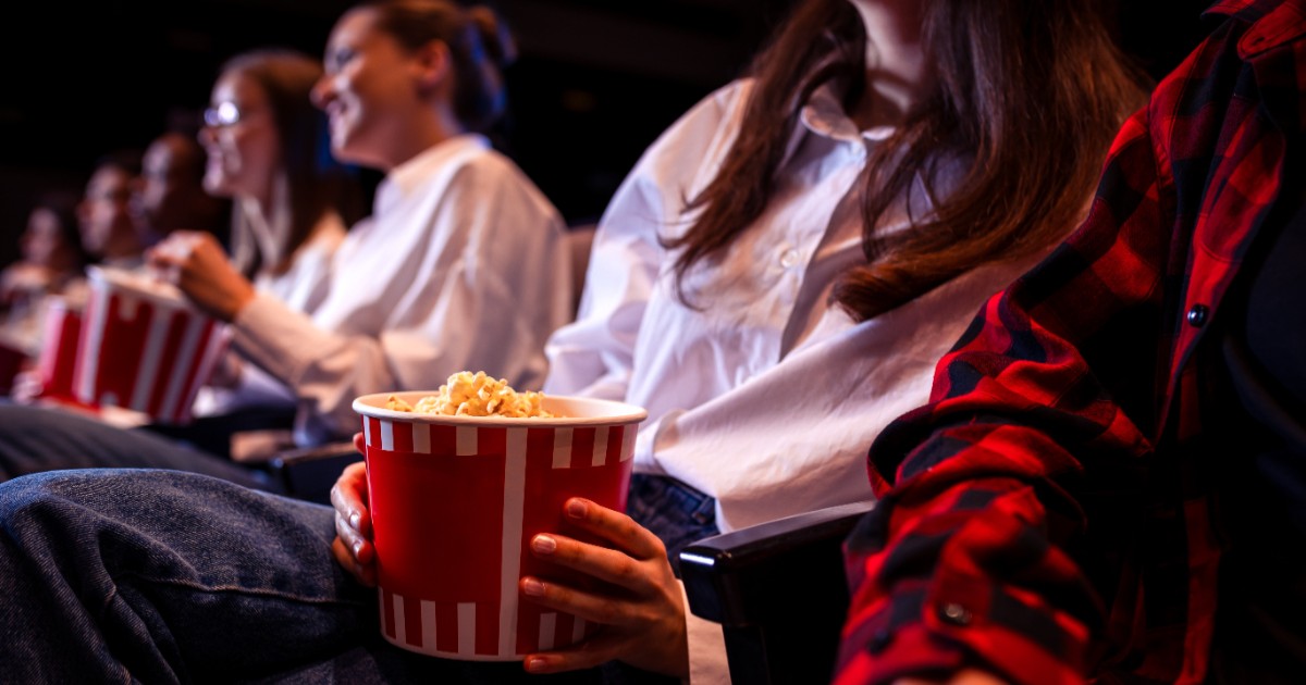 Oameni într-o sală de cinema, cu popcorn