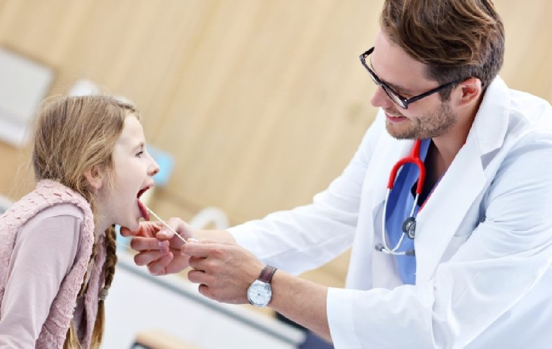 Medic  examinand un copil pentru suspiciune de streptococ beta hemolitic 