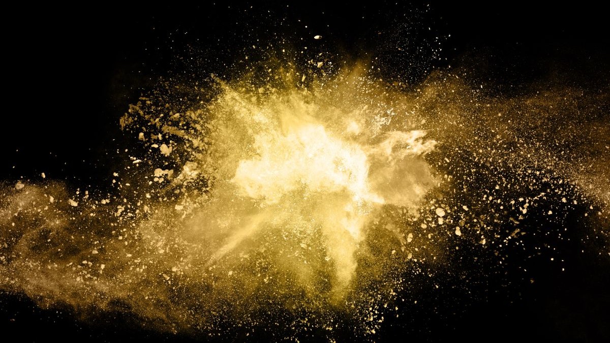 Explozie de pulbere aurie pe fundal negru. Mișcare înghețată.