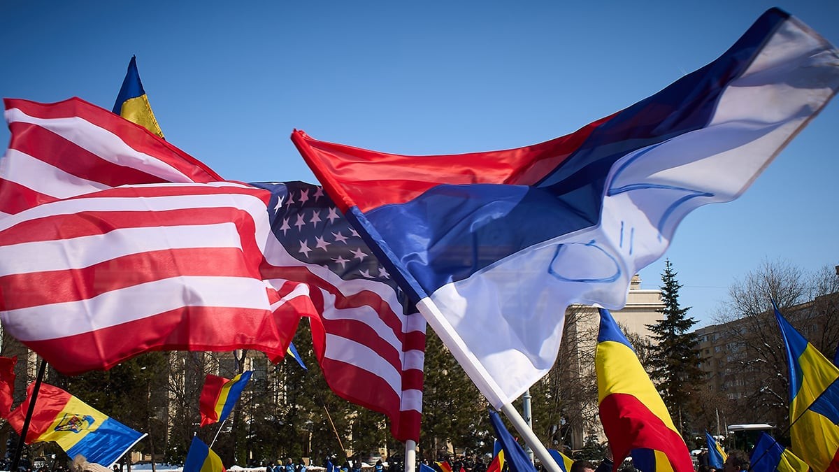 București, România. 21 februarie 2025: Un bărbat flutură steagul SUA și steagul Rusiei inversat în timpul unui protest al susținătorilor ultranaționalistului de extremă dreapta Călin Georgescu, în fața guvernului român.