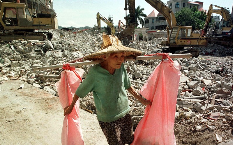 A woman carries her belongings through a destroyed building in Fengyuan, central Taiwan 20 October 1999 one month after the powerful earthquake struck the island. Most damaged buildings have been torn down and preparations made for reconstruction. AFP PHOTO,Image: 282660657, License: Rights-managed, Restrictions: , Model Release: no