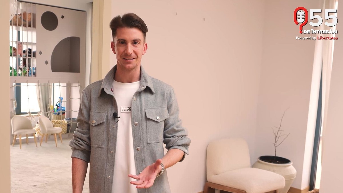 Rareș Cojoc, intr-o camasa de blugi purtata peste un tricou alb, la el in casa, in picioare