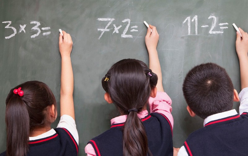 Trei elevi care rezolvă exerciții de matematică la tablă