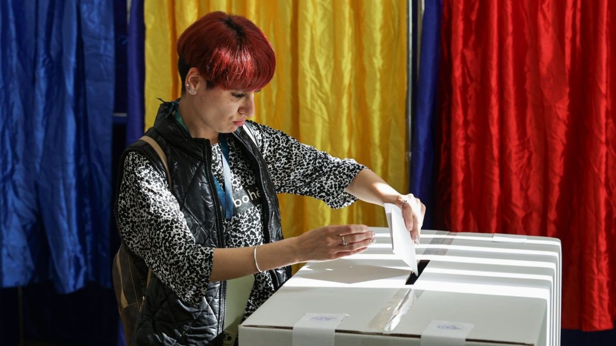 O tânără cu bluză și vestă bagă votul în urnă la alegerile prezidențiale din 4 mai 2025, București