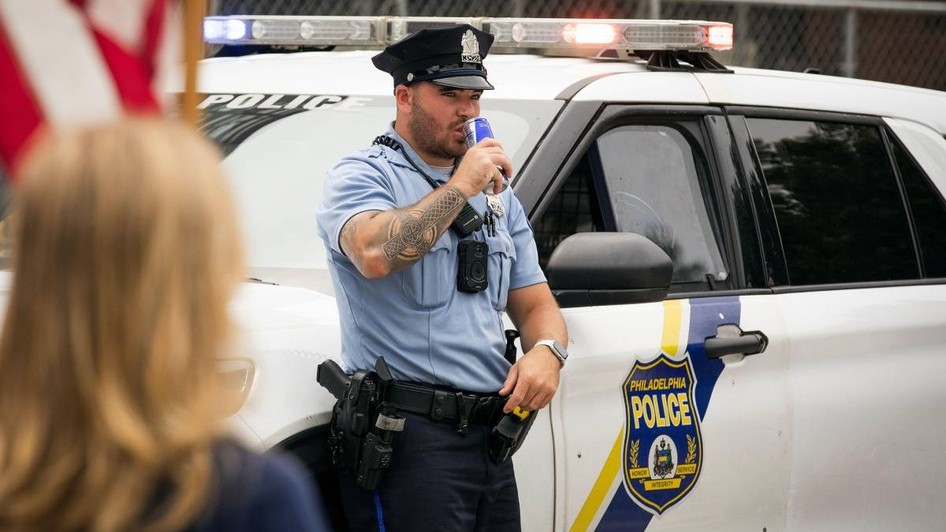 Un polițist din Philadelphia se sprijină pe mașina sa.