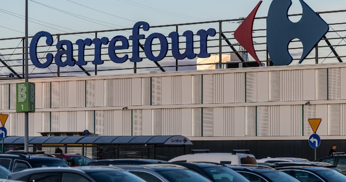 Logo-ul lanțului francez de supermarketuri Carrefour este vizibil pe acoperișul unui magazin de mari dimensiuni, în timp ce mașinile sunt parcate în suburbia Varșoviei, Polonia, pe 23 septembrie 2025.