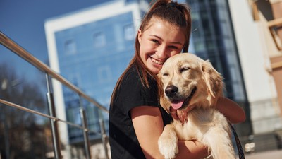 O tânără îmbrățișează un câine