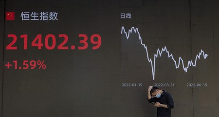 Un bărbat se oprește în fața unui ecran care arată cele mai recente trenduri din economie și bursa de valori din Shanghai, China, 15 iunie 2022.