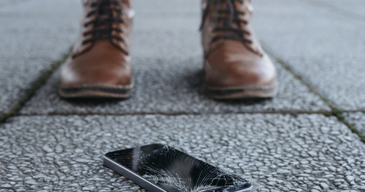 Merită să îţi asiguri telefonul mobil? - Imagine cu un telefon mobil deteriorat după ce a căzut pe asfalt