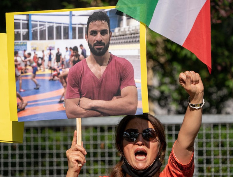 O femeie protestează față de executarea luptătorului iranian Navid Afkari în fața Ambasadei Iranului la Berlin, ținând în mână o pancartă cu imaginea sportivului. FOTO: EPA-EFE/ALEXANDER BECHER