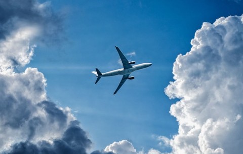 Un avion zburând prin cerul albastru și printre nori