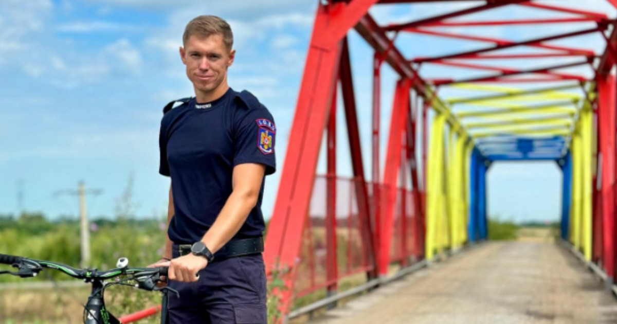 Ștrango Marius îmbrăcat în uniformă de pompier, lângă o bicicletă.