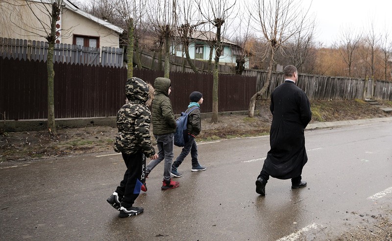 Preotul Alexandru Posteanu, urmărit de trei copii din sat