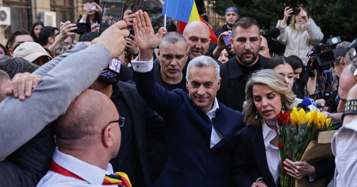 Călin Georgescu, cu brațul drept ridicat în sus, salută mulțimea venită să-l suțină când și-a depus candidatura