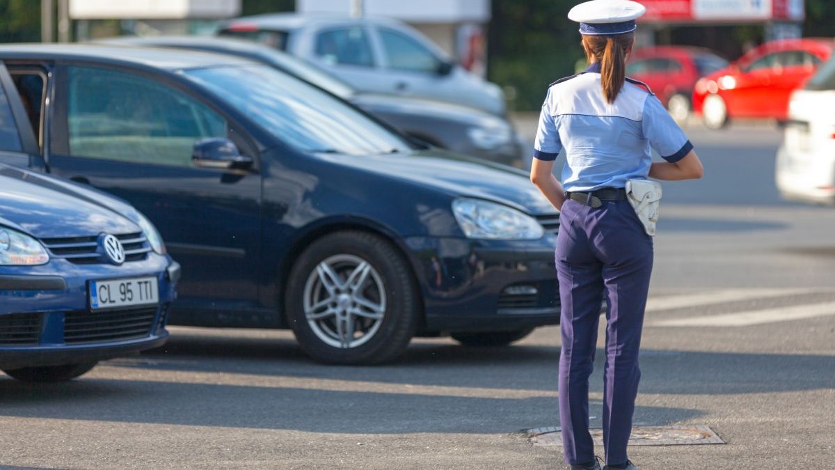 Polițistă de la Rutieră, îmbrăcată în uniformă, fotografiată din spate, pe o stradă din București, cu mașini pe fundal
