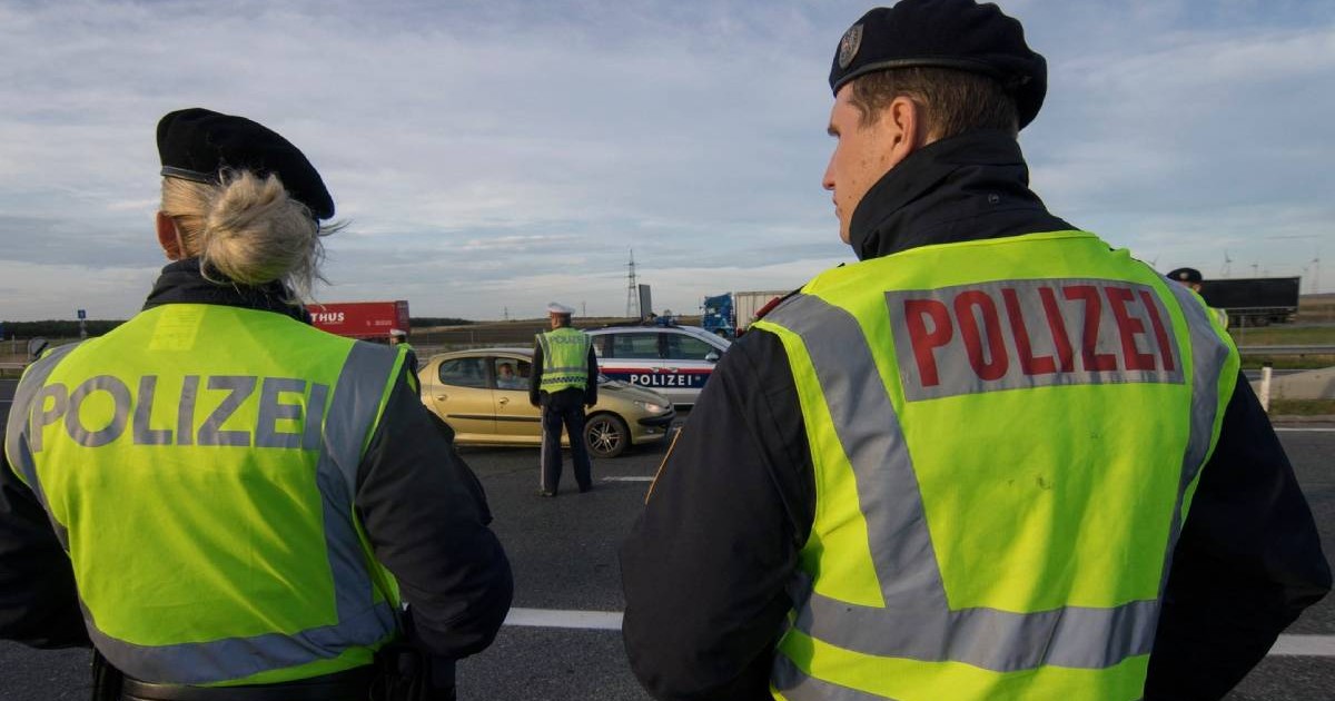 Doi polițisti austrieci, o femeie si un barbat, cu spatele , participă la controalele la frontieră pe autostrada A4 lângă Nickelsdorf, la punctul de trecere a frontierei austro-ungare, în primele ore ale dimineții