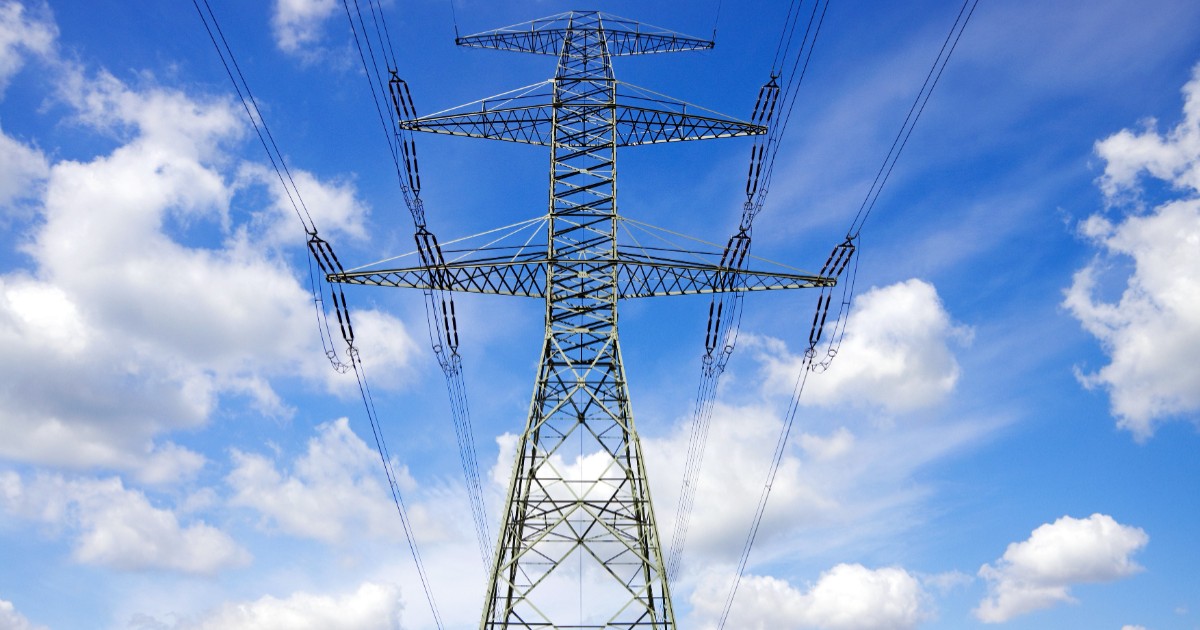 Austria este acuzată că nu lasă energia ieftină din Vest să ajungă în sud-estul Europei, inclusiv România, ceea ce face ca zona să aibă prețuri mai mari. Stâlp de înaltă tensiune pe fundal cu cer albastru și nori albi