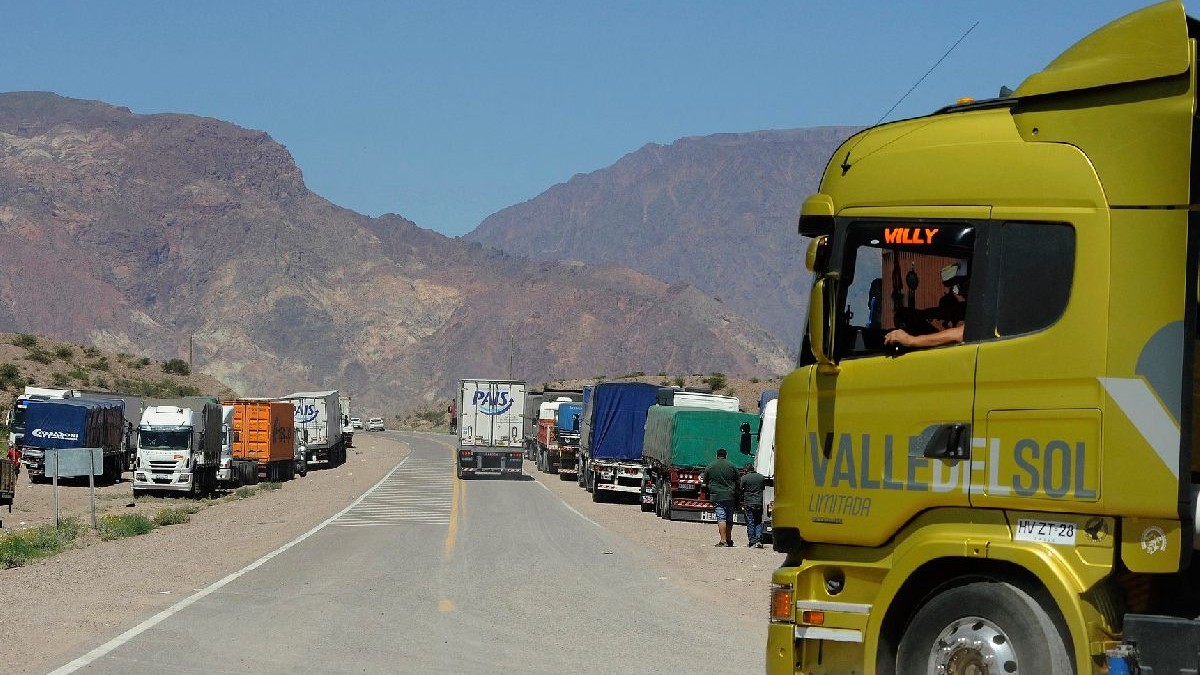 Imaginea ilustrativă care prezintă o autostradă cu un șir lung de camioane parcate de-a lungul acesteia. În prim-plan se află un camion galben strălucitor cu inscripția „VALLE DEL SOL LIMITADA” imprimată pe lateral