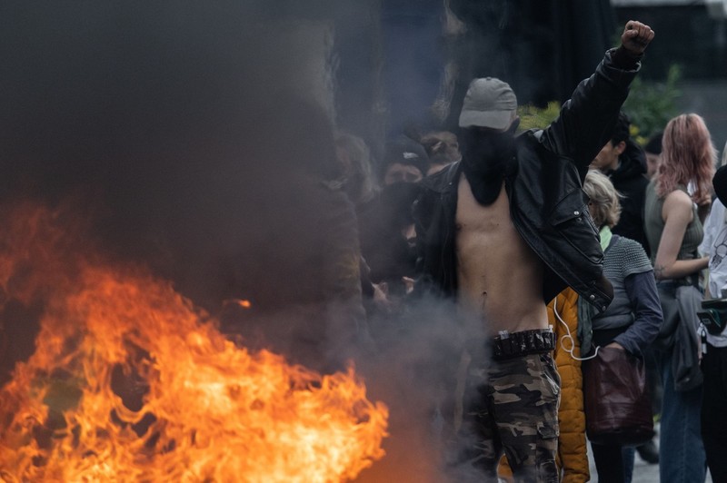 A protester in front of a fire during a demonstration on a national action day, a week after the government pushed a pensions reform through parliament without a vote, using the article 49.3 of the constitution, in Bordeaux, southwestern France, on March 23, 2023. French President defiantly vowed to push through a controversial pensions reform on March 22, 2023, saying he was prepared to accept unpopularity in the face of sometimes violent protests. Protest In Bordeaux Against The Macron's Pension Reform For The 9th Day Of Strikes, France - 23 Mar 2023,Image: 764869847, License: Rights-managed, Restrictions: , Model Release: no
