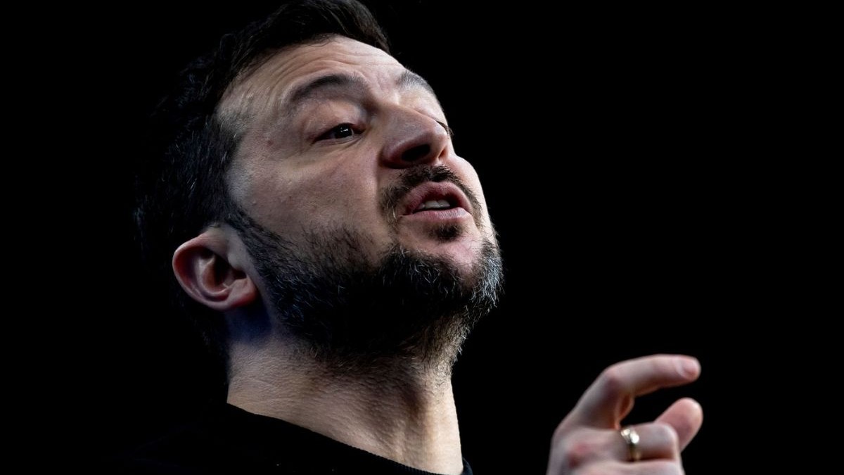 Volodimir Zelenski, explicând ceva la o conferință de presă, pe un fundal negru