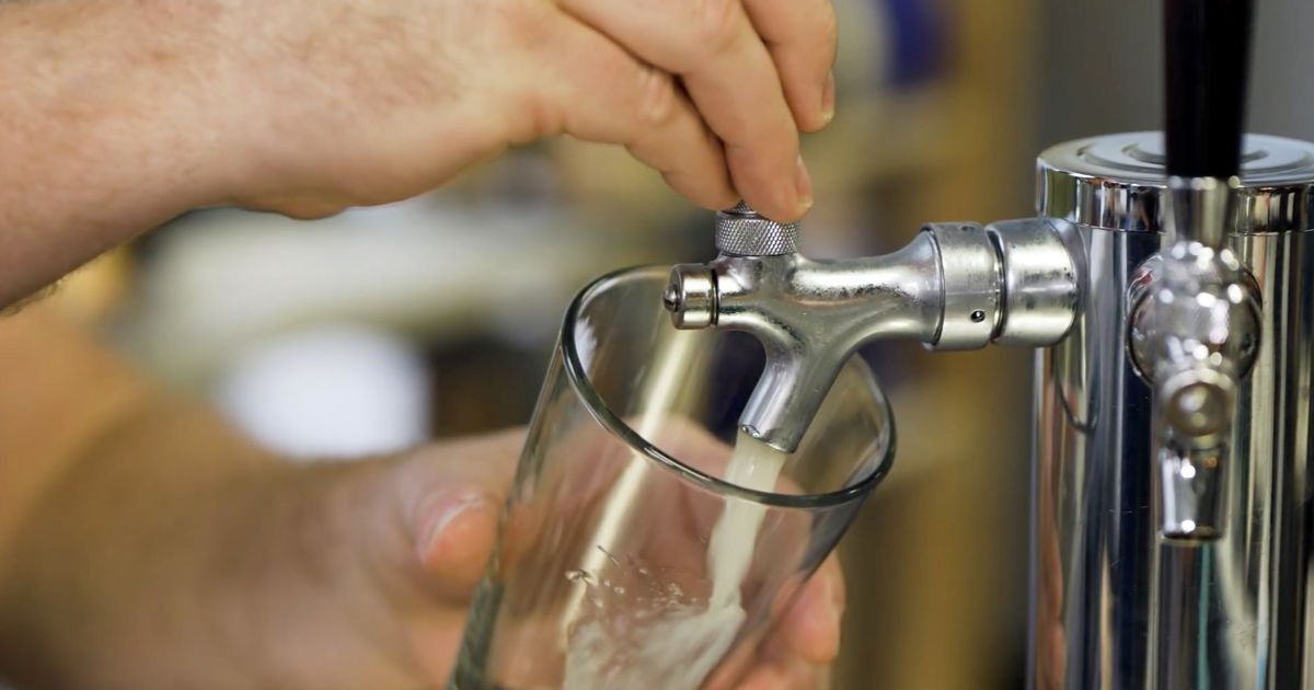 Un barman umple cu grijă o halbă de bere