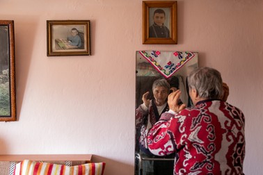 Mioara își dă jos baticul. În camera lor, pe perete sunt portretele copiilor din prima căsătorie a lui Gheorghe