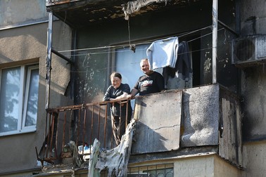 Mariupol, 27 mai: Locuitorii privesc de pe un balcon al unei clădiri avariate. Foto: Hepta
