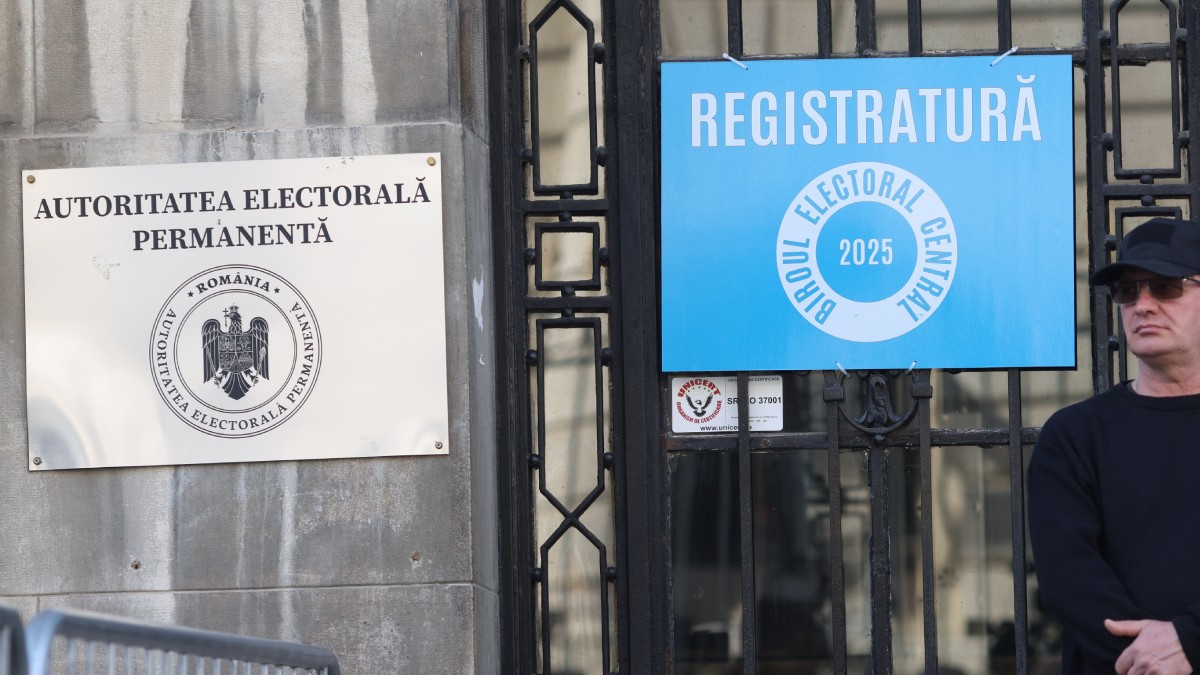 sediul Autorității Electorale permanente, pe care în stânga, pe perete, este sigla, în dreapta este o ușă pe care este pus un afis cu un fundal albastru pe care scrie „registratură, biroul electoral central 2025”
