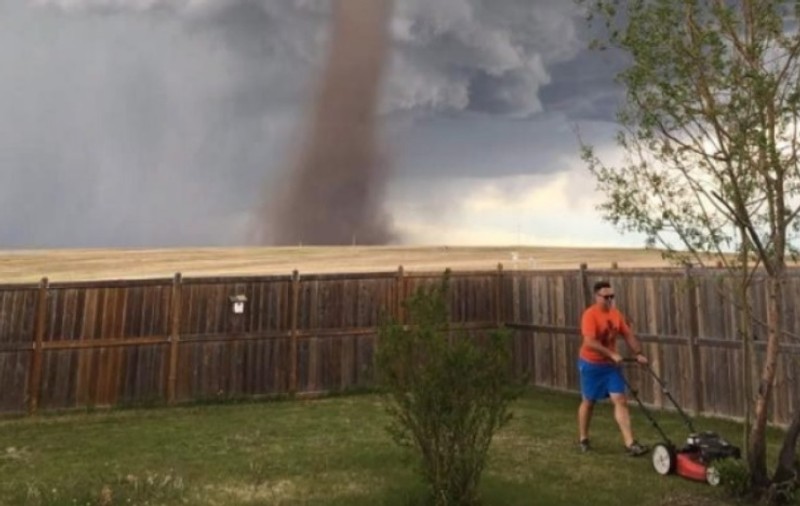Fotografia care a devenit virală: Un bărbat tunde liniștit gazonul, în timp ce în spatele său e o tornadă