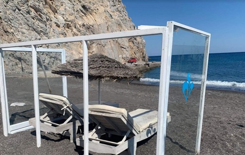 Șezlonguri împrejmuite de pereți din pexiglas. Soluția găsită de o plajă din Santorini pentru protecția turiștilor