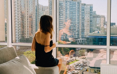 Femeie privind pe geamul apartamentului ei