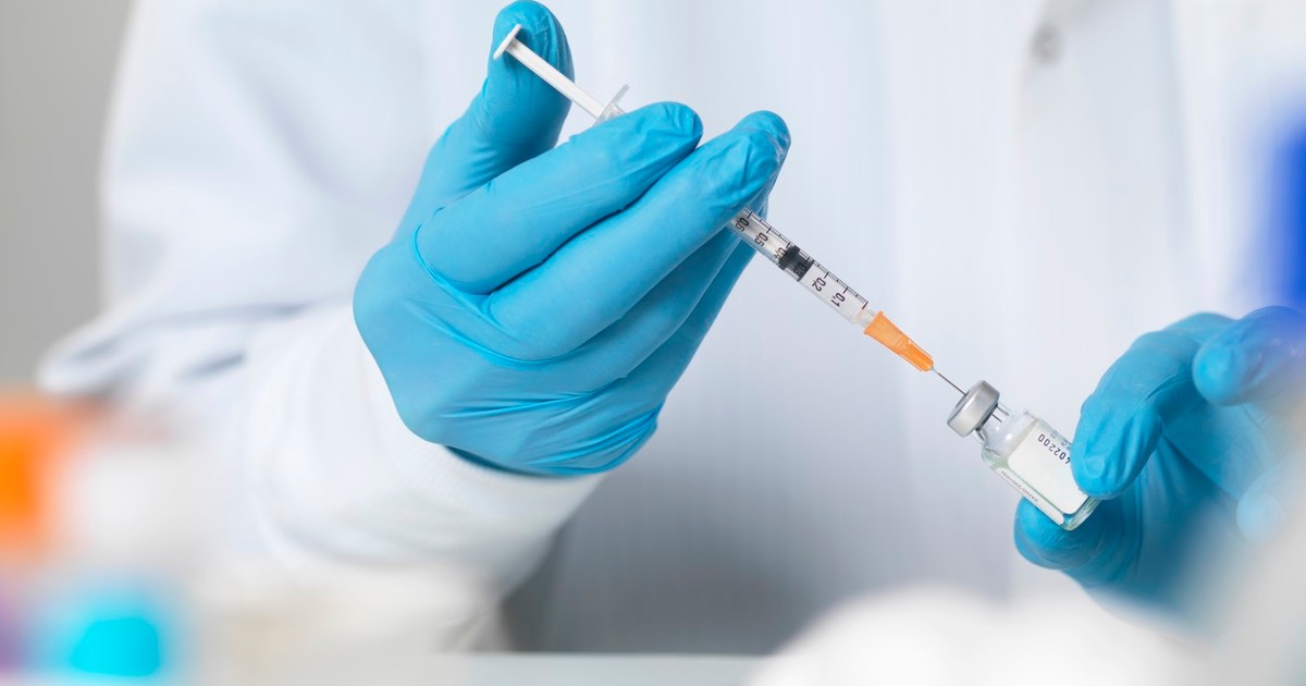 Un doctor care ține în mână o seringă si o fiola de vaccin