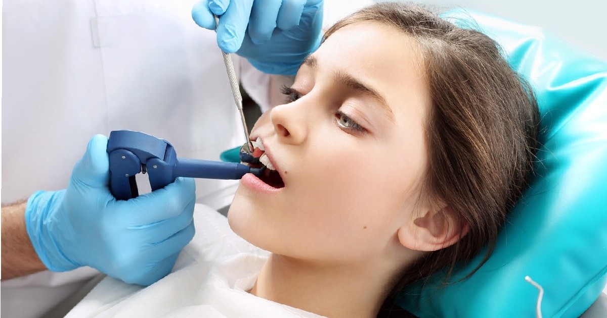 un copil pe un scaun dentar în timpul unui tratament dentar. tratamentul pierderii dinților, un copil la dentist. cariile dentare la copii, principii de igienă orală. sigilarea dinților, un copil la dentist. un cabinet dentar, un copil pe un scaun dentar. sigilare cu lumină, un copil într-un cabinet dentar