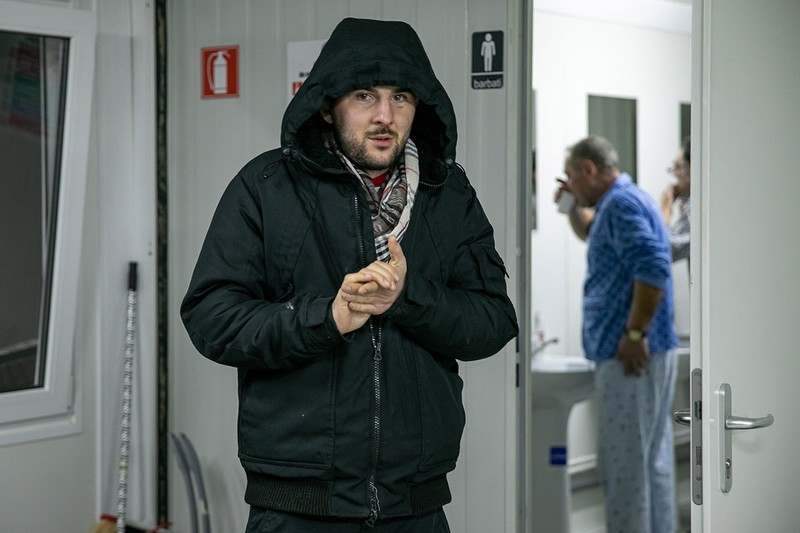 Cristi știe că nu e pe lista pentru locuri în pat, dar speră că va fi primit să doarmă pe jos în adăpost. Până va afla, a intrat câteva minute pentru a merge la toaletă și pentru a-și încălzi mâinile.
