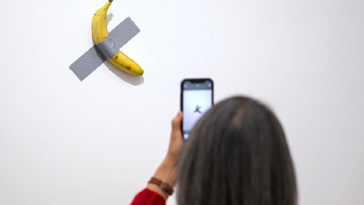 Un vizitator admiră opera de artă „Comedian” a artistului italian Maurizio Cattelan în timpul vernisajului pentru presă al expoziției „Dimanche sans fin. Maurizio Cattelan et la Collection du Centre Pompidou”.