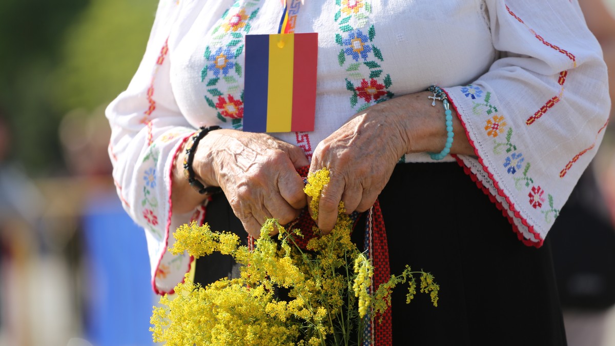 Festivalul RomânIA Autentică va avea loc pe 23 și 24 iunie. O bâtrână îmbrăcată în ie, cu un mic tricolor la gât