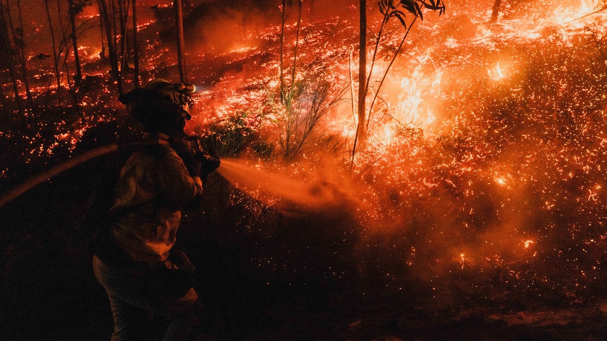 Imagine cu un pompier care încearcă să stingă un incendiu de vegetație din Galicia, Spania