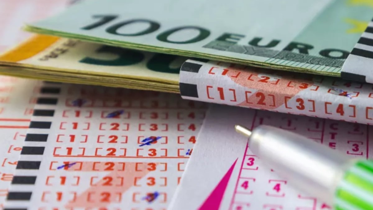 Un bilet de loto pe care sunt așezate mai multe bancnote de euro.