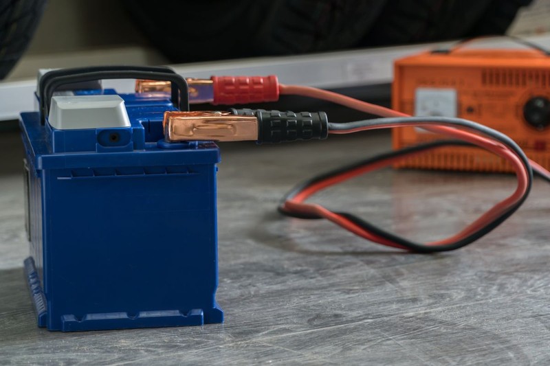 Recharging the car battery on a wooden background.