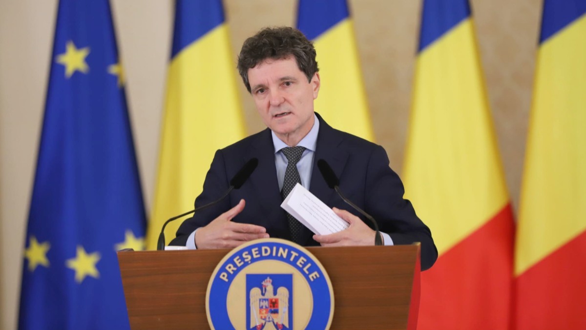 Nicușor Dan, susținând o declarație de presă, având în spate steagurile României și ale Uniunii Europene.
