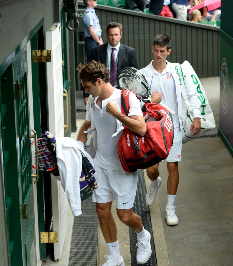 epa04844136 Roger Federer of Switzerland (L) and Novak Djokovic of Serbia leave Centre Court as rain interrupts the men's final of the Wimbledon Championships at the All England Lawn Tennis Club, in London, Britain, 12 July 2015. EPA/FACUNDO ARRIZABALAGA EDITORIAL USE ONLY/NO COMMERCIAL SALES