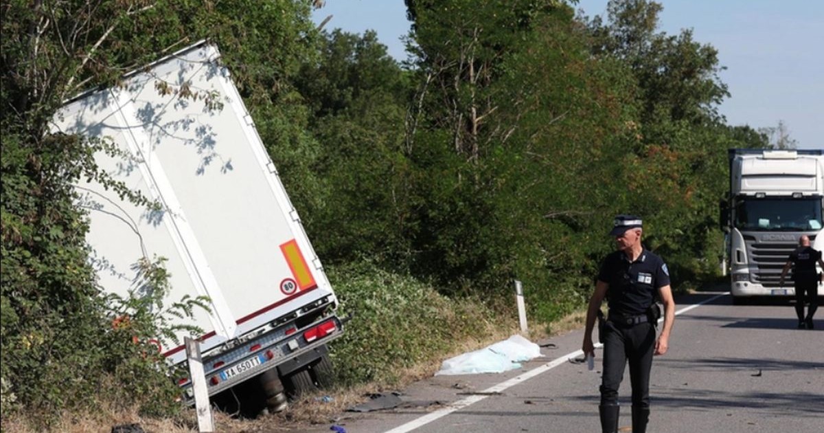 TIR-ul condus de un șofer român a ajuns într-un șanț, pe partea stângă, unde este și o zonă cu pomi, în față se vede un polițist, iar în spate pe șosea este un camion alb staționat și un bărbat
