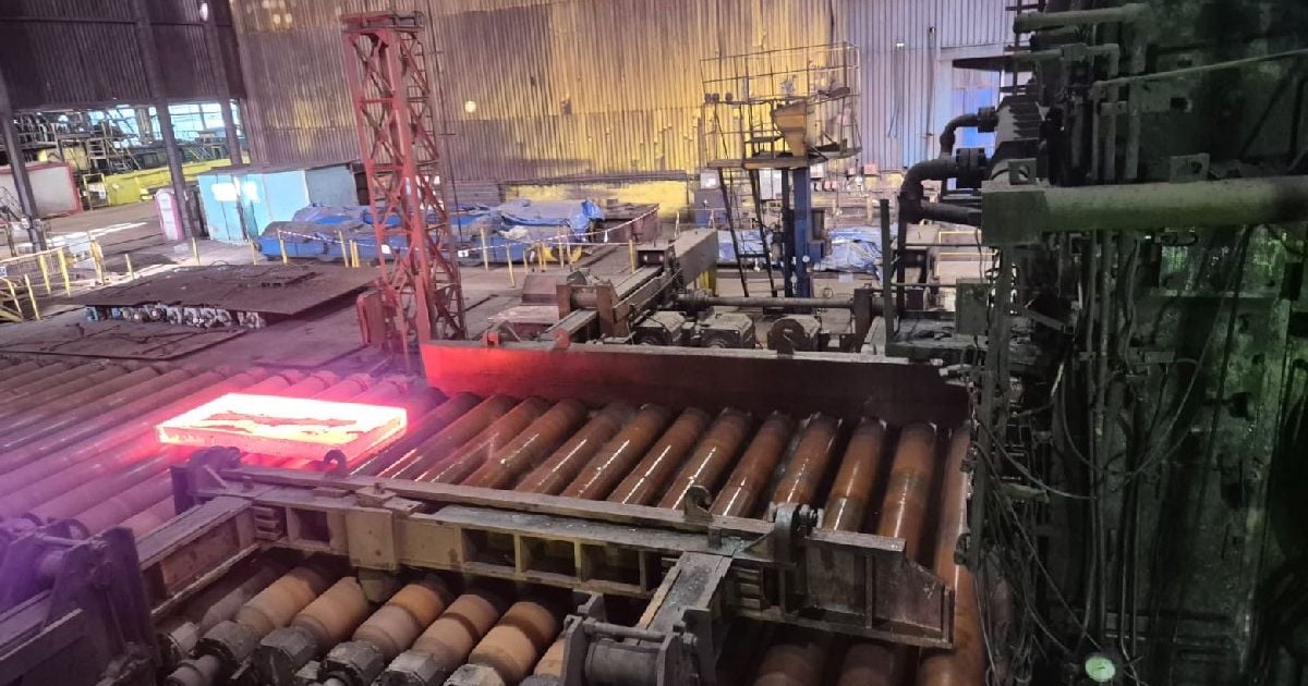 Interiorul unei fabrici industriale cu structuri metalice cilindrice mari, umeroase țevi.