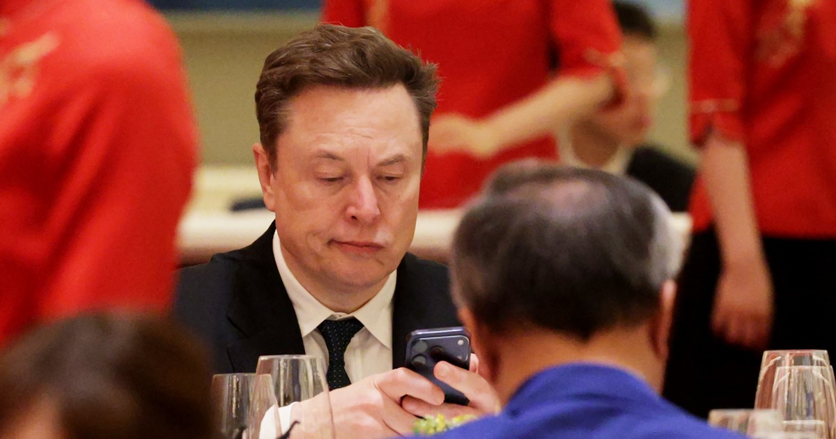 Elon Musk se uită încruntat la telefonul său în timpul bufetului dat de Xi Jinping în China.
