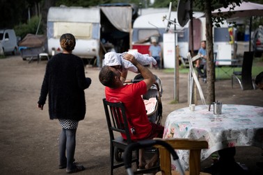 Un bărbat ține în brațe un copil într-o mahala populată aproape exclusiv de români, mulți dintre ei din minoritatea romă, în Nantes. Foto: Profimedia Images