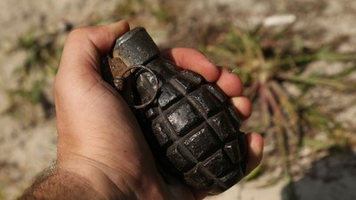 Grenadă veche și ruginită în mâna unui bărbat