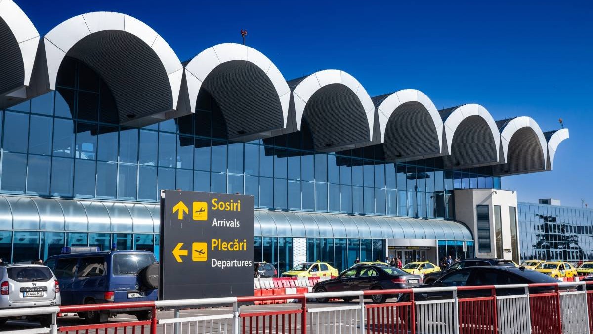 Parcarea din fața Aeroportului Otopeni, plină, într-o zi însorită.