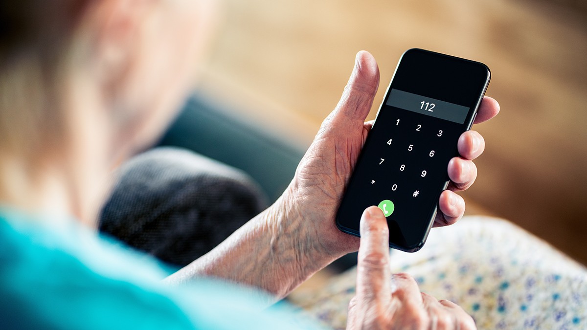 O femeie în vârstă care ține în mână un telefon și sună la 112
