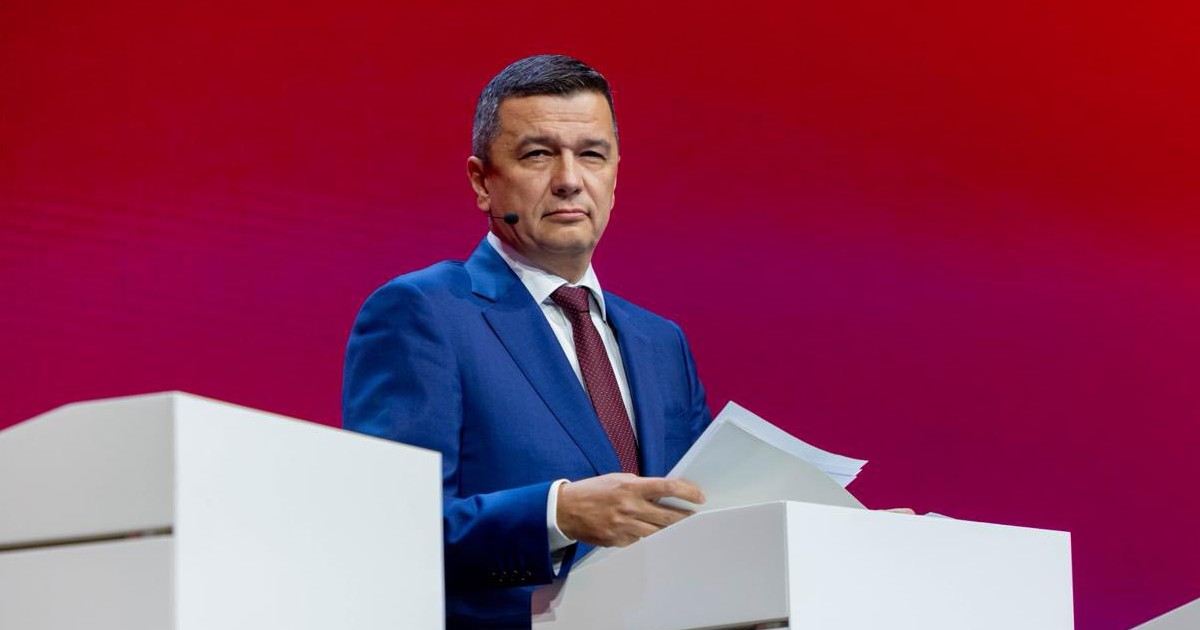 Sorin Grindeanu la costum și cravată grena privește în depărtare.