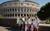 O mamă cu cinci copii pozează având Colosseumul ca fundal, în centrul istoric al orașului Roma, Italia.